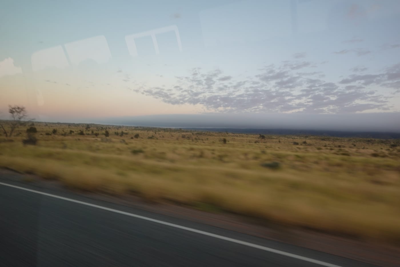 Outback roadside seen through a bus window at dawn.