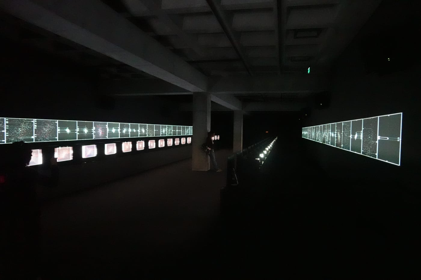 Long corridor with rows of small video screens.