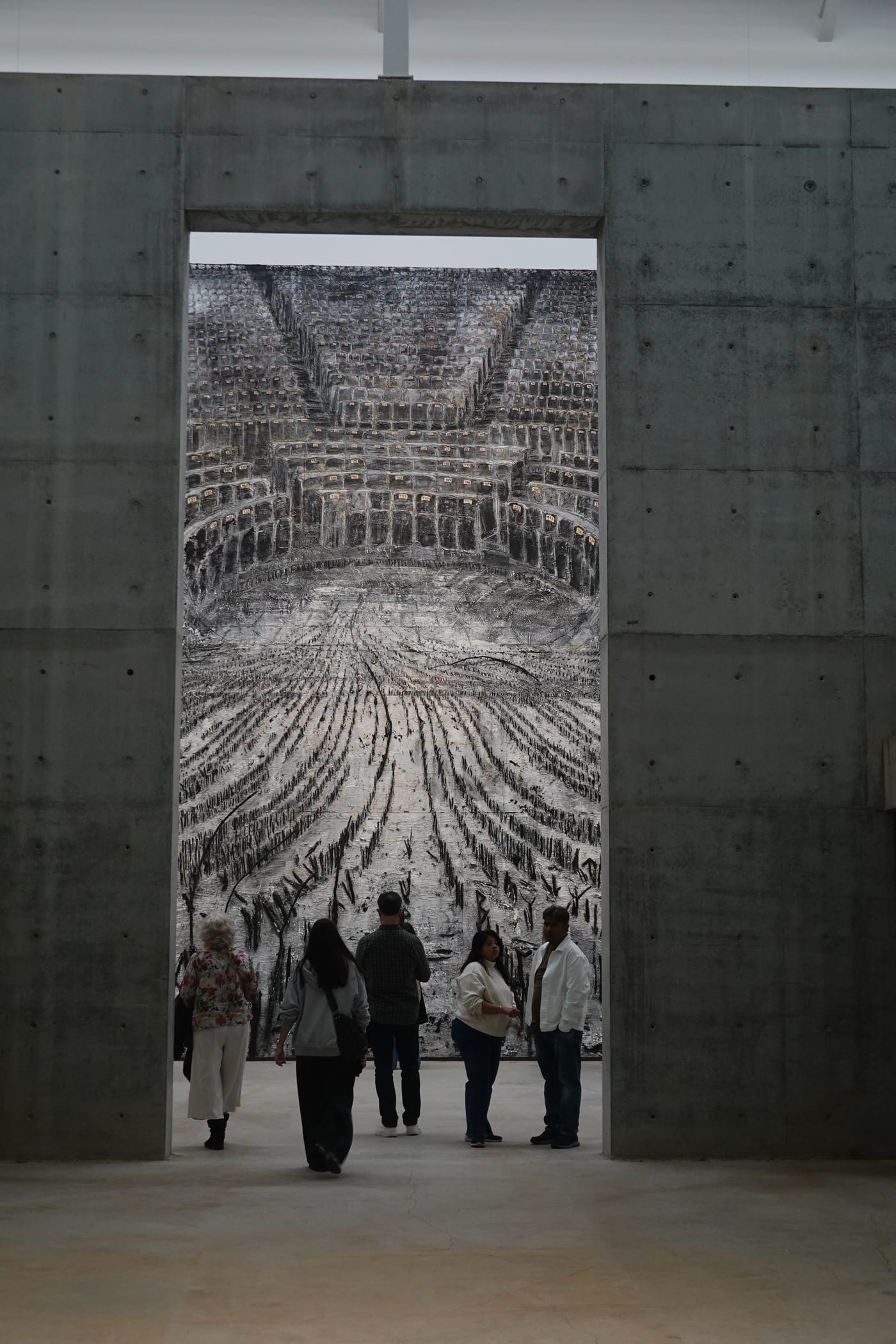 Visitors viewing a tapestry through a concrete tunnel.
